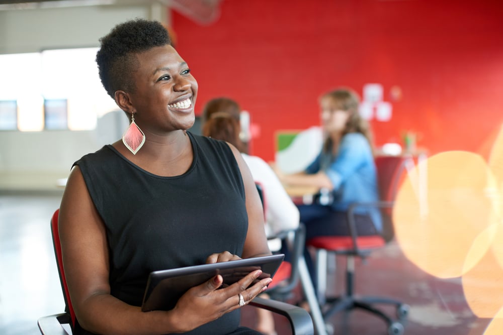 Confident female designer working on a digital tablet in red creative office space