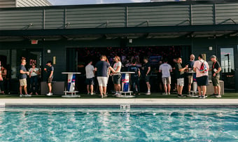 Quantum Workplace employees standing by a poolside having drinks.